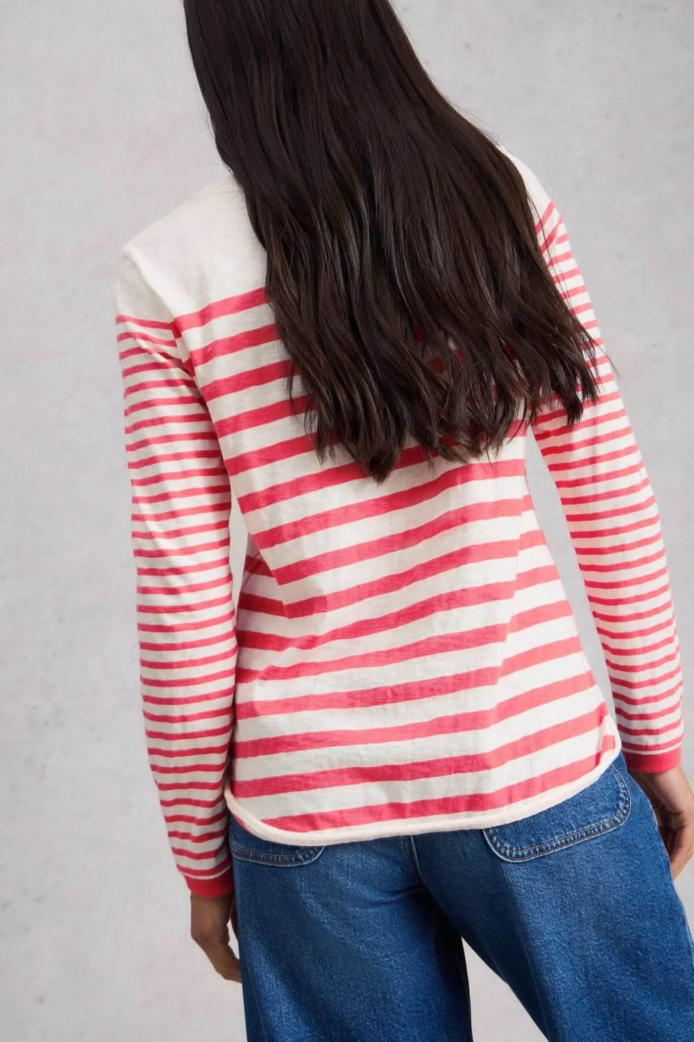 Dos d'une femme portant un t-shirt rayé à manches longues, idéal pour un look décontracté avec un motif rayé rouge et blanc.