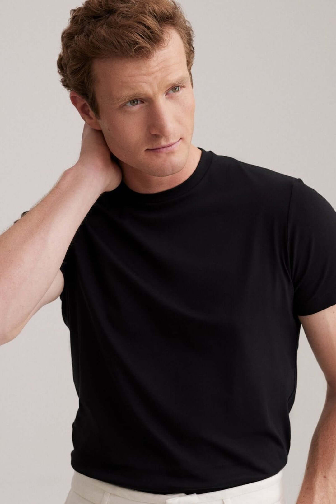 Homme portant un t-shirt noir moderne à col rond, idéal pour une tenue décontractée et élégante.
