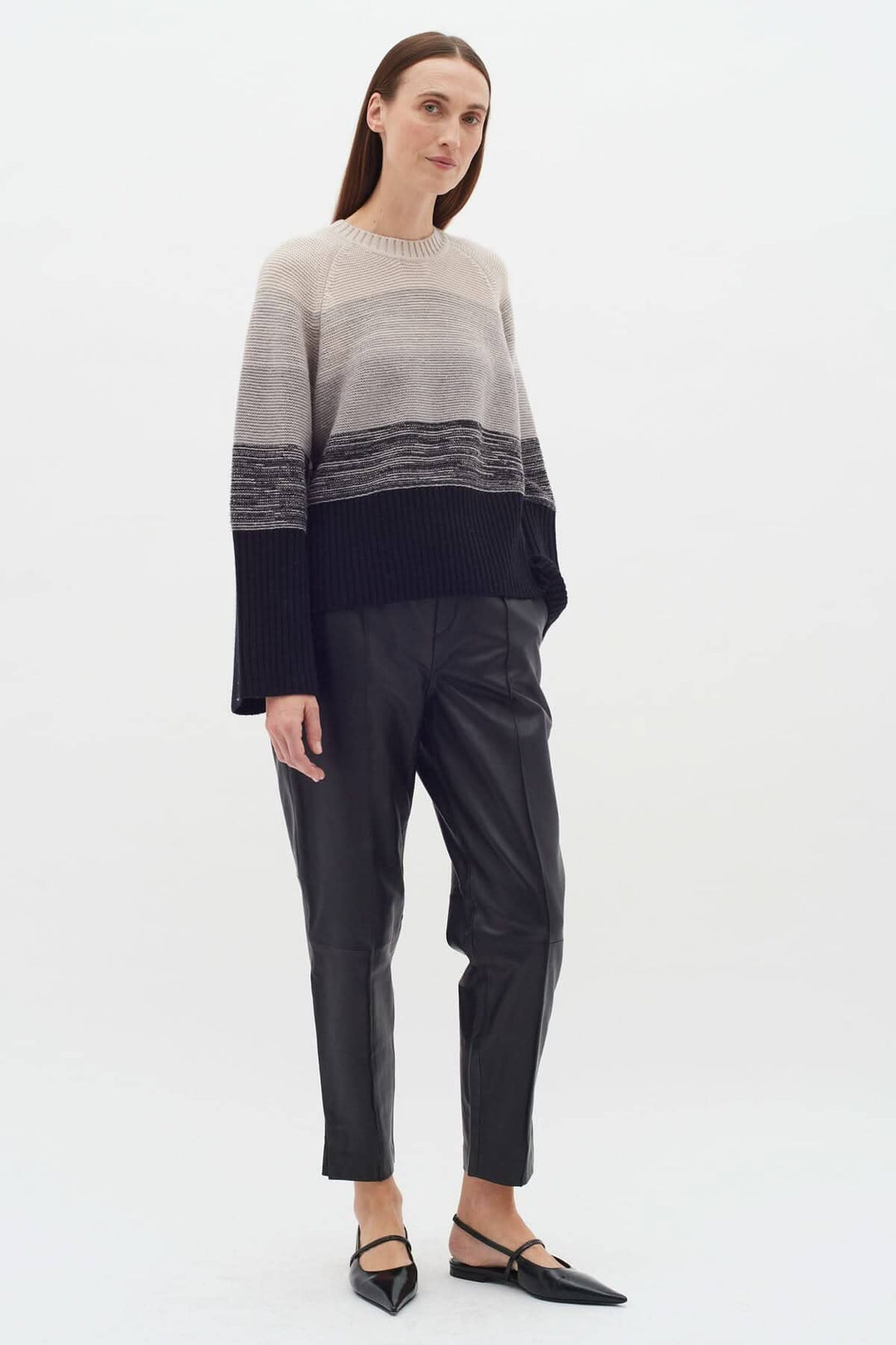 Tricot Kaxy en gros rayures neutres, col rond, manches longues, coupe ample, porté avec pantalon en cuir.