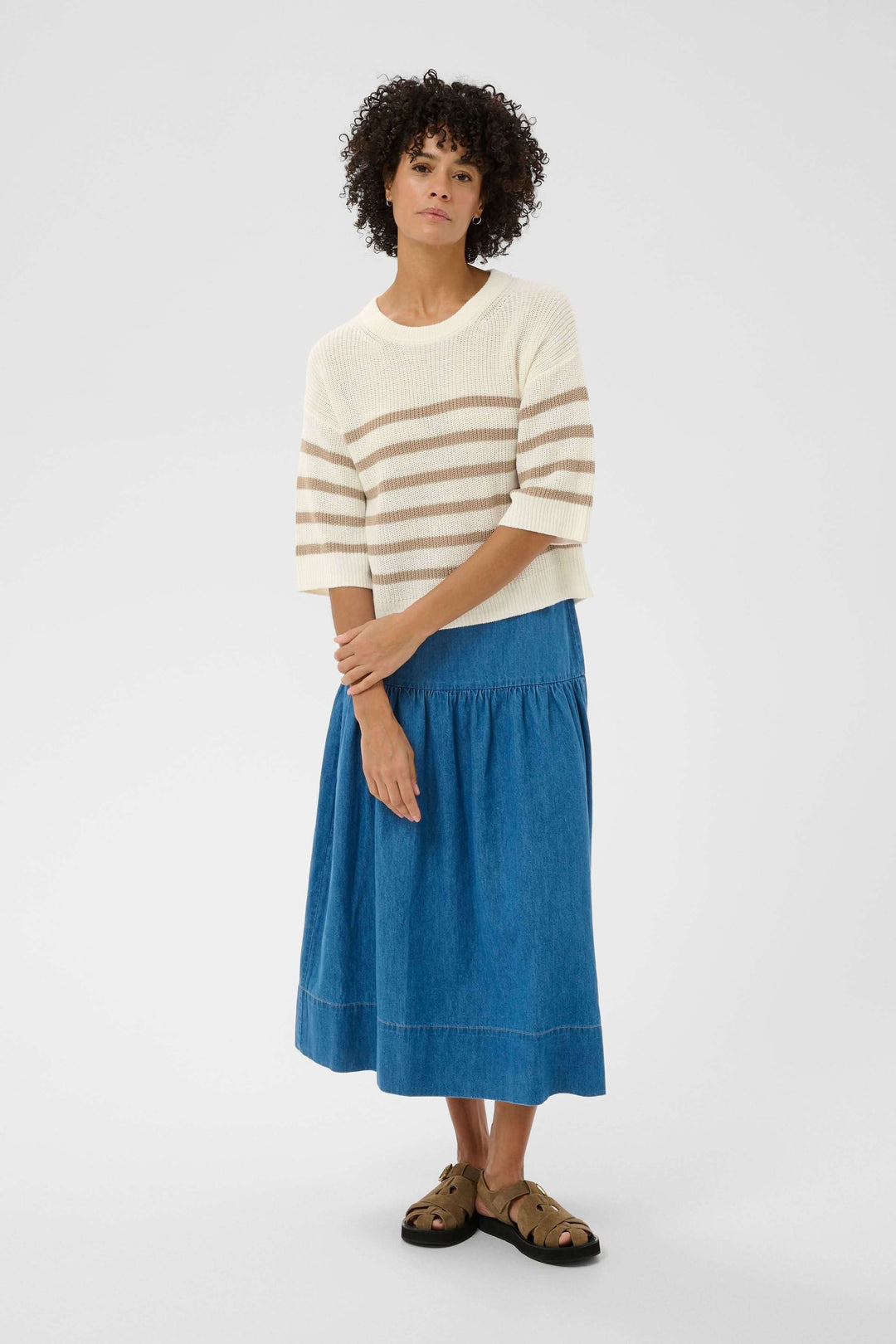 Femme portant un tricot lin et coton Aliza à rayures, avec une jupe bleue mi-longue, tenue décontractée pour mi-saison.