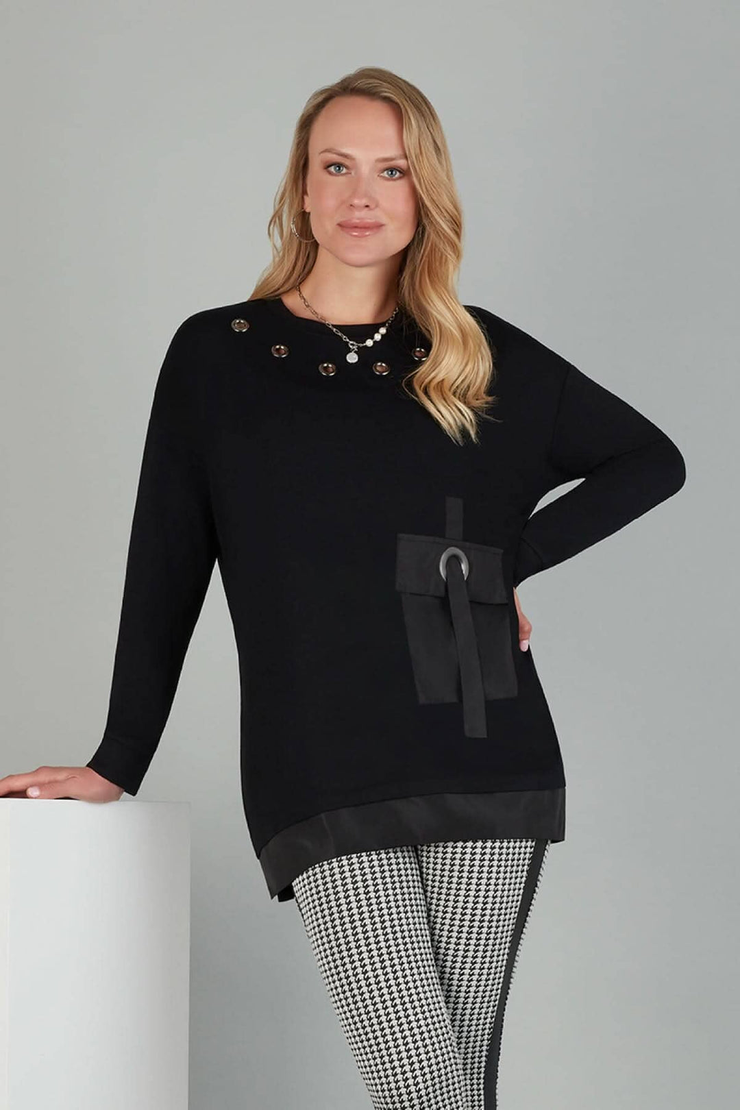 Tunique noire en tricot avec œillets argent, manches longues et poche en satin, modèle décontracté.