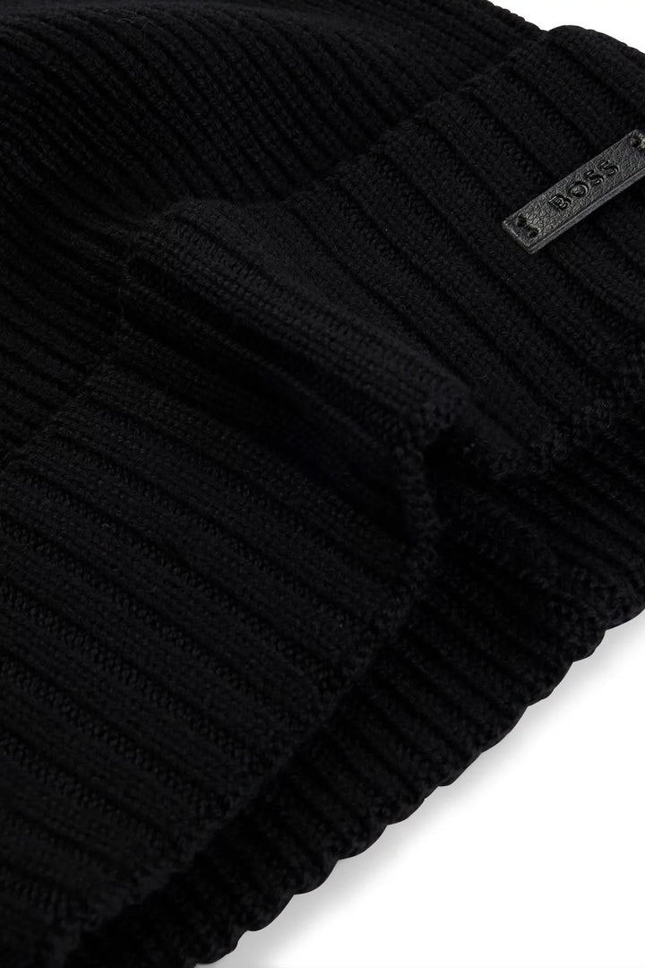 Bonnet en laine noir avec structure côtelée et étiquette logo BOSS en tissu synthétique.