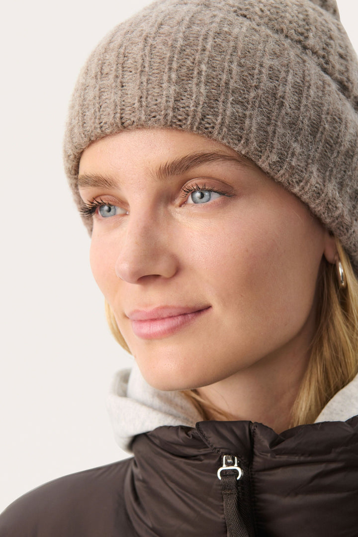 Femme portant une tuque moelleuse en tricot côtelé, parfaite pour les journées froides.