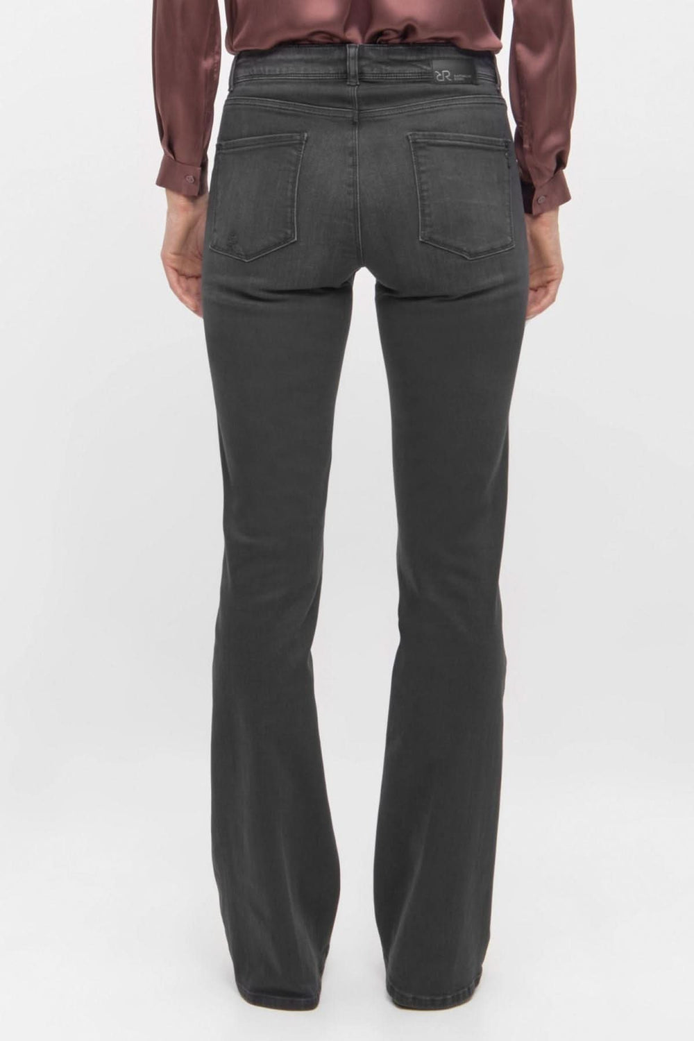 Jean noir à coupe évasée vu de dos, stylisé avec une chemise en satin, offrant un look chic et moderne.