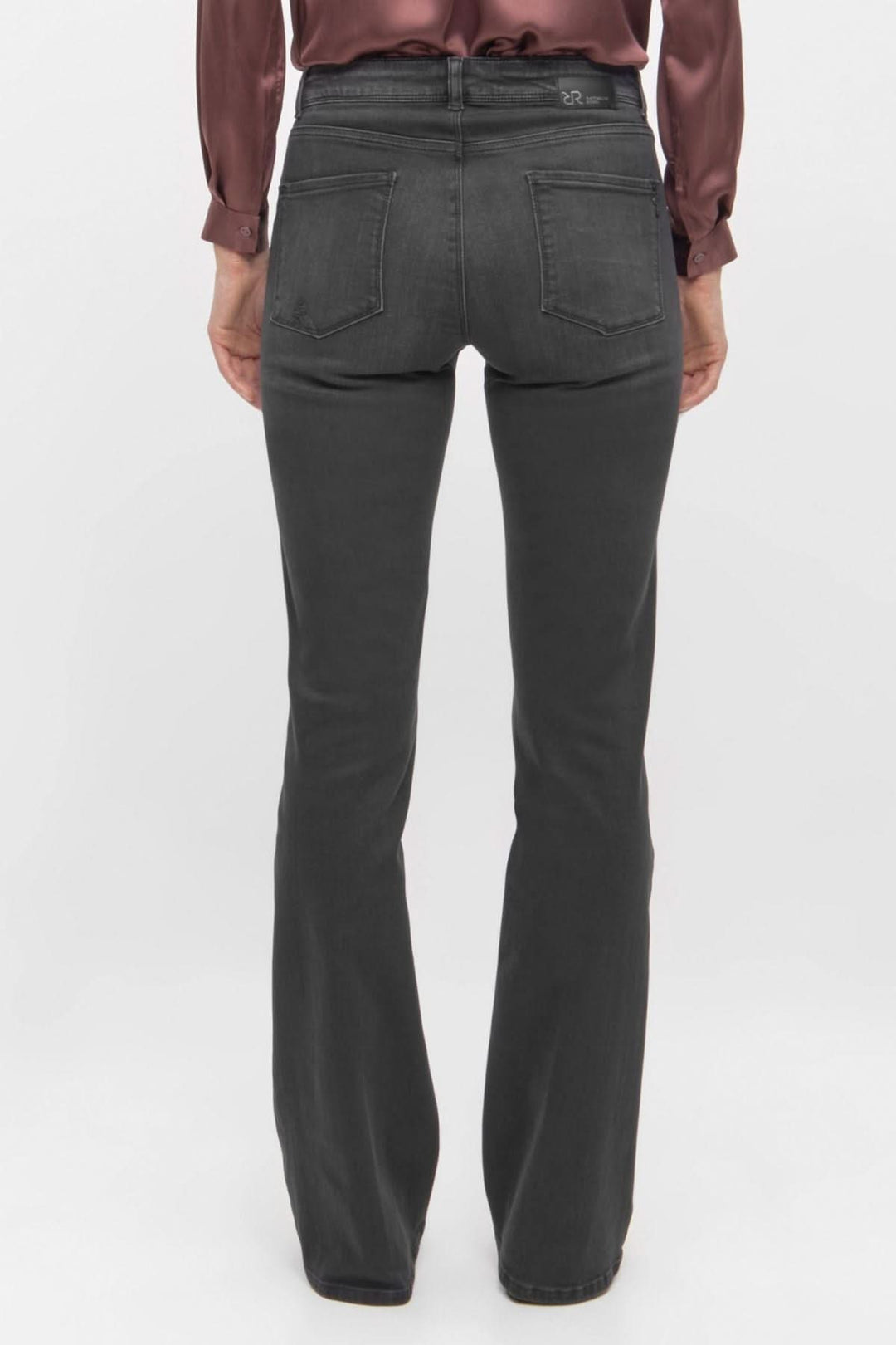 Jean noir à coupe évasée vu de dos, stylisé avec une chemise en satin, offrant un look chic et moderne.