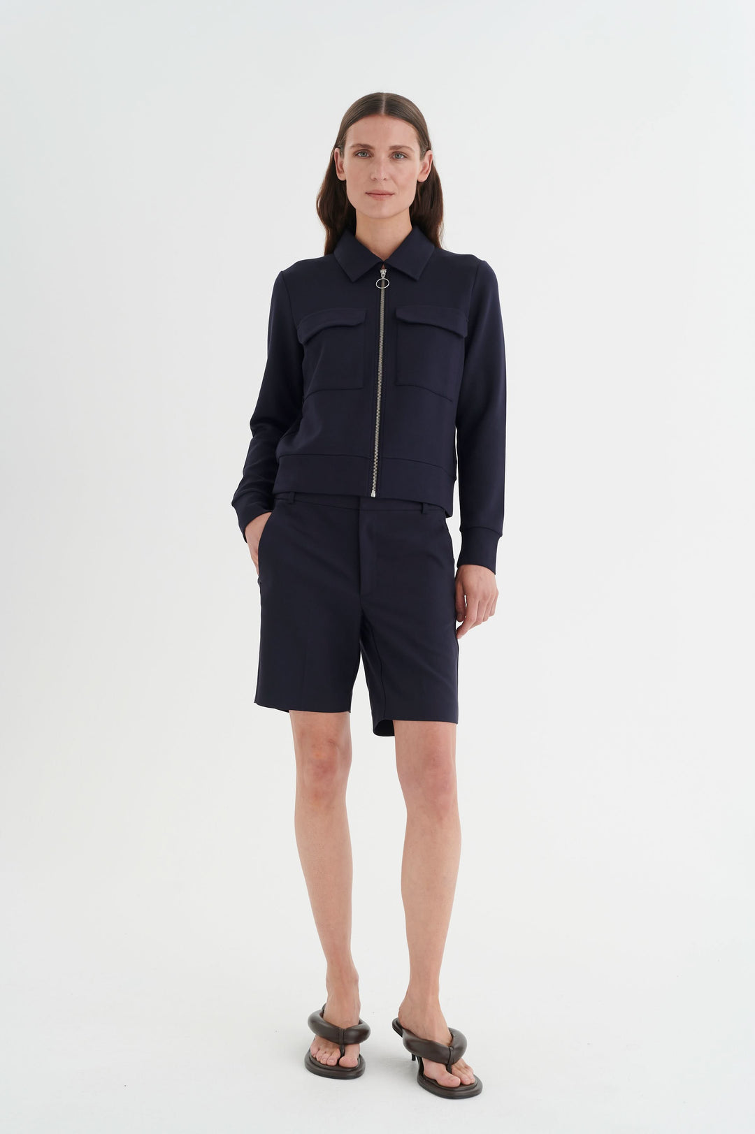 Veste Beca à manches longues, fermeture éclair, poches poitrine, associée à un short, look chic et urbain.