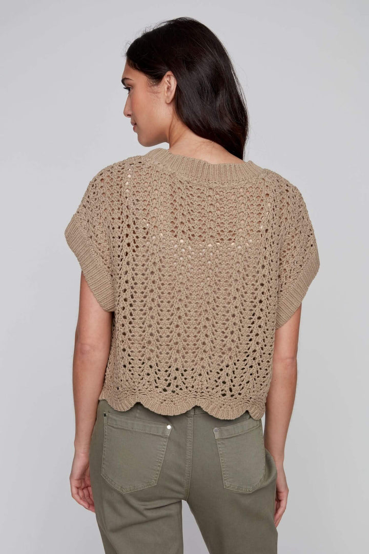 Veste au crochet beige à manches courtes, coupe ouverte, ajourée, portée avec un pantalon vert, vue de dos.