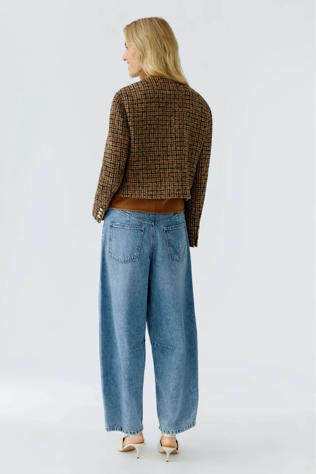 Veste courte à carreaux, boutons dorés, en laine texturée, portée avec un jean pour un look moderne et élégant.
