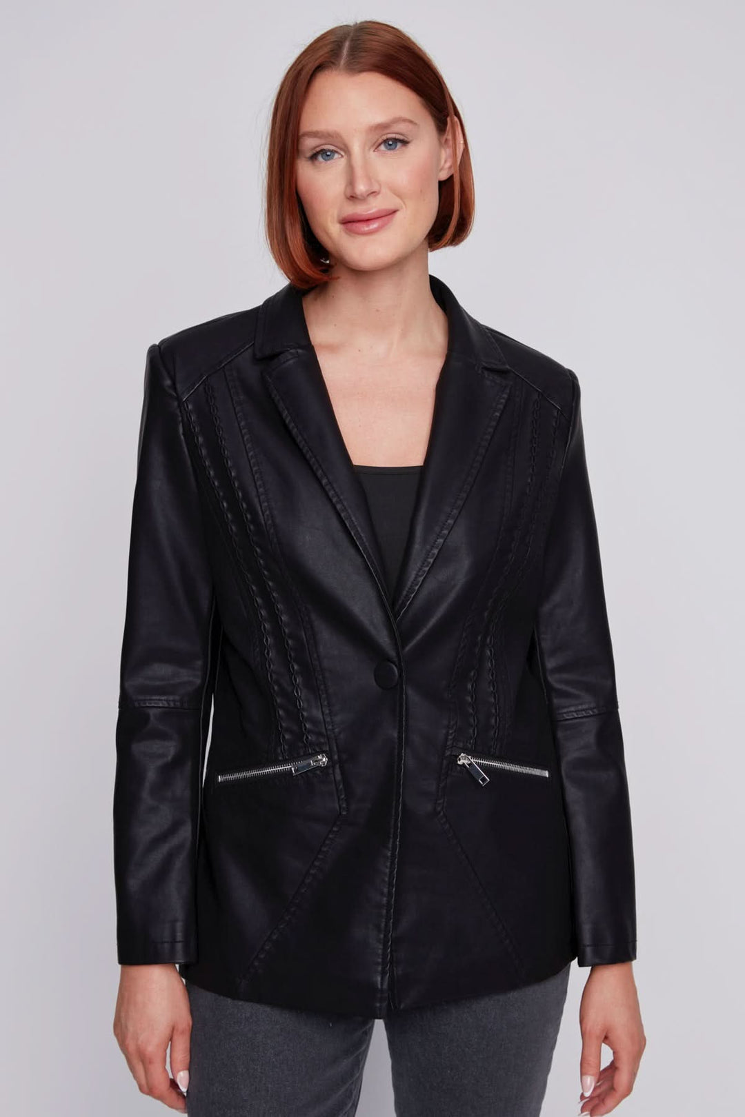 Veste effet cuir noire avec coupe structurée et coutures décoratives, portée par une femme souriante.