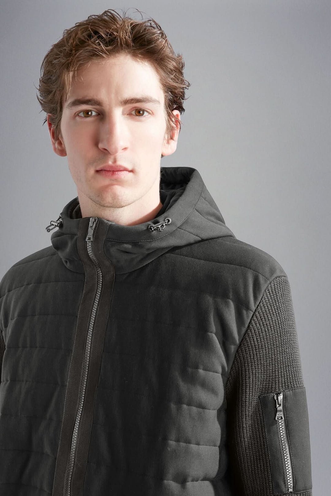 Homme portant une veste imperméable à capuchon Paul & Shark, mélange de matelassage et tricot pour confort et chaleur.