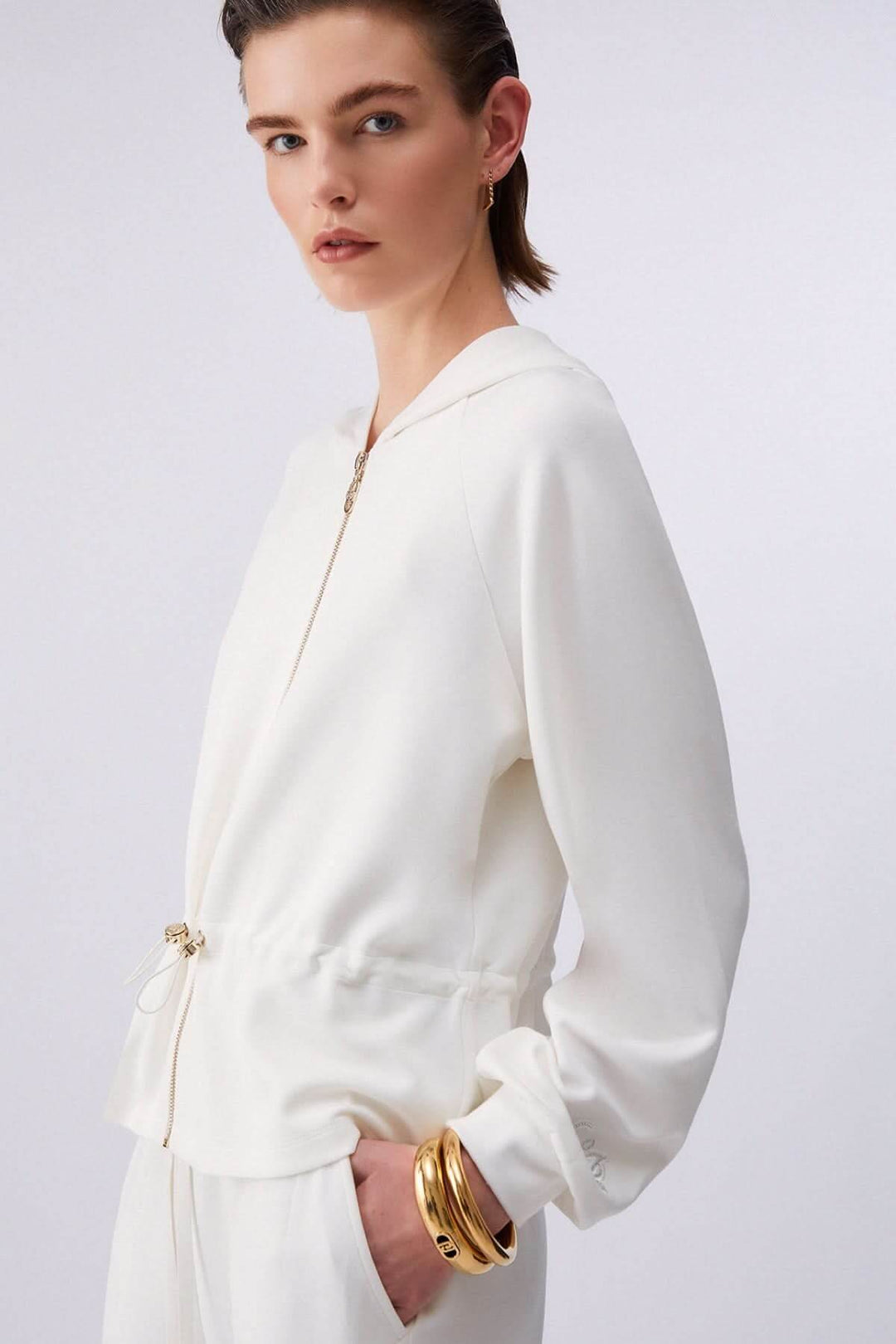 Femme portant une veste légère à capuchon avec cordon ajustable, silhouette moderne, élégante, idéale pour la mi-saison