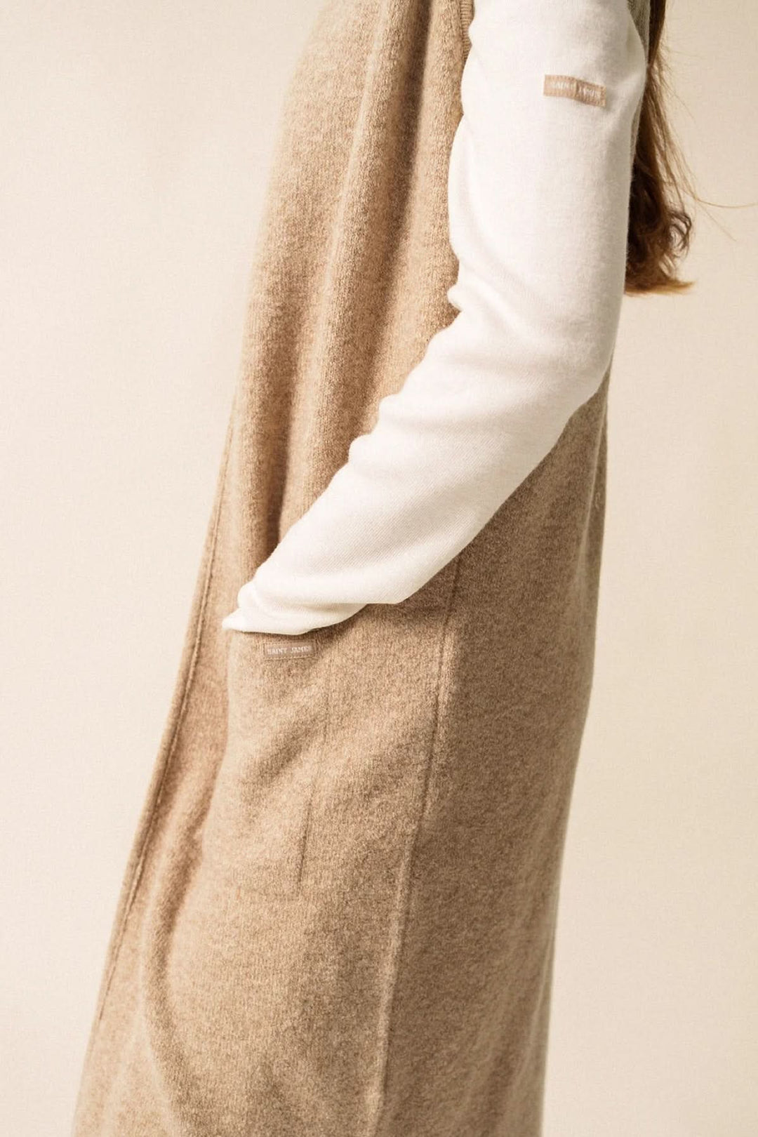 Veste longue en maille beige, sans manches, avec poches, idéale pour un look moderne et cosy.