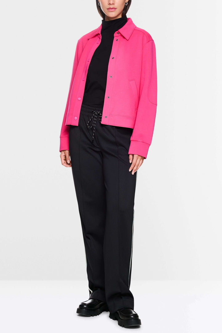 Veste moderne rose portée avec un t-shirt noir et un pantalon noir, affichant un style décontracté et tendance.