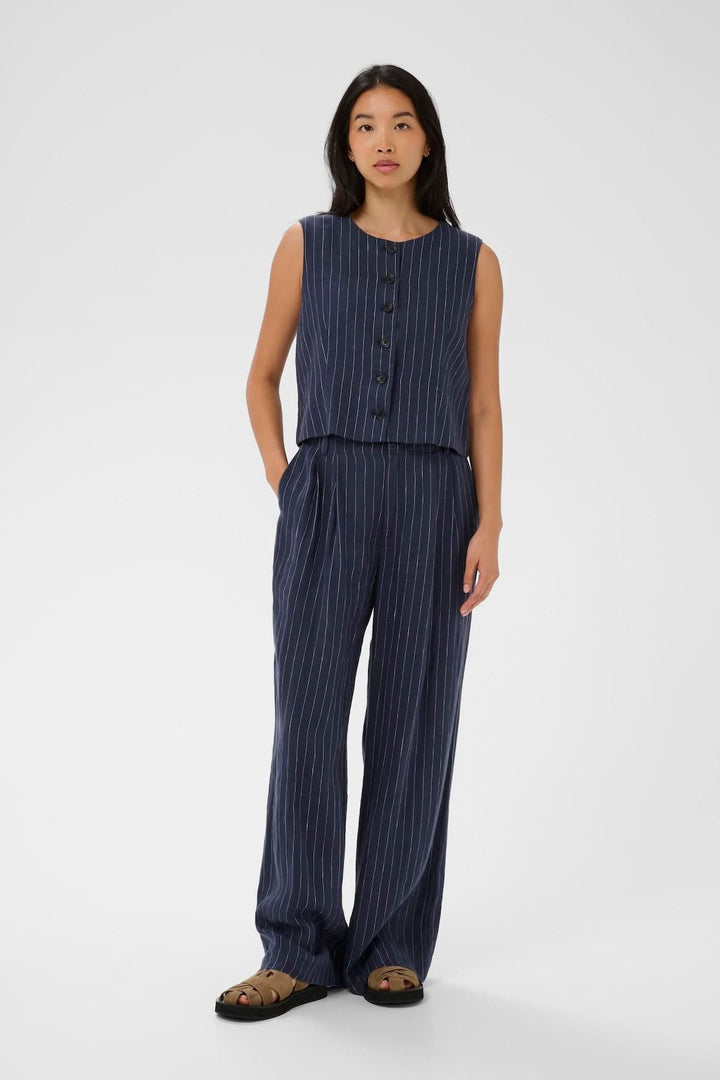 Veste sans manches Azania avec motif rayé vertical, coupe droite et fermeture boutonnée portée par une femme.