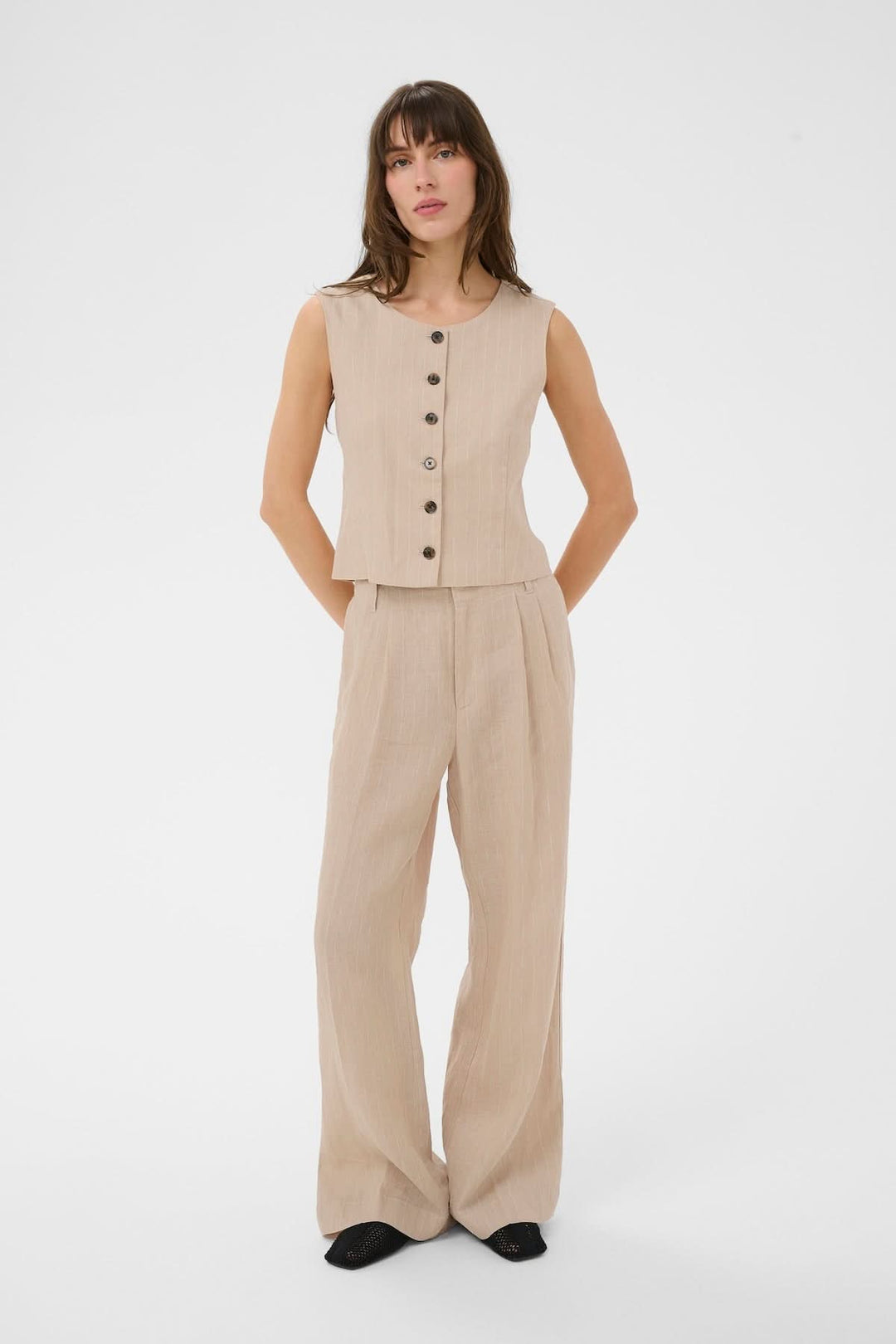 Veste sans manches Azania en lin beige avec motif rayé vertical et fermeture boutonnée, portant une coupe structurée et moderne.
