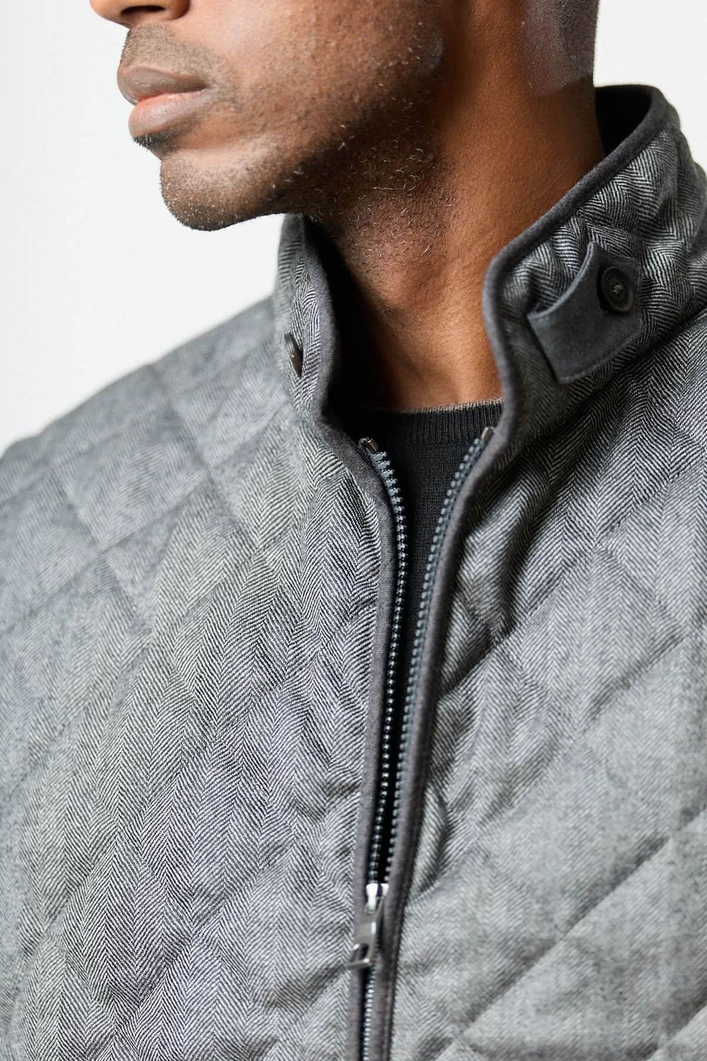 Veste sans manches matelassée en laine à motif chevrons, élégante texture herringbone, confection raffinée pour tenue urbaine.