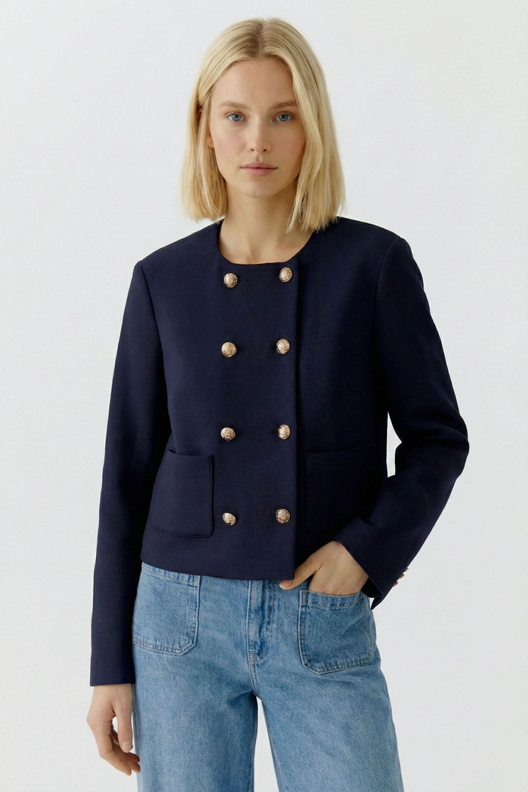 Femme portant une veste structurée à boutons décoratifs, style sophistiqué et chic, encolure ronde, coupe droite.