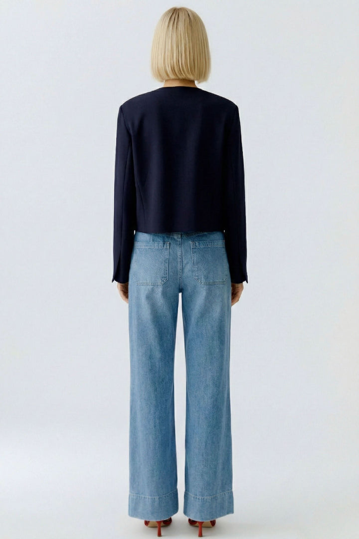 Veste structurée à boutons décoratifs vue de dos, portée avec un jean.