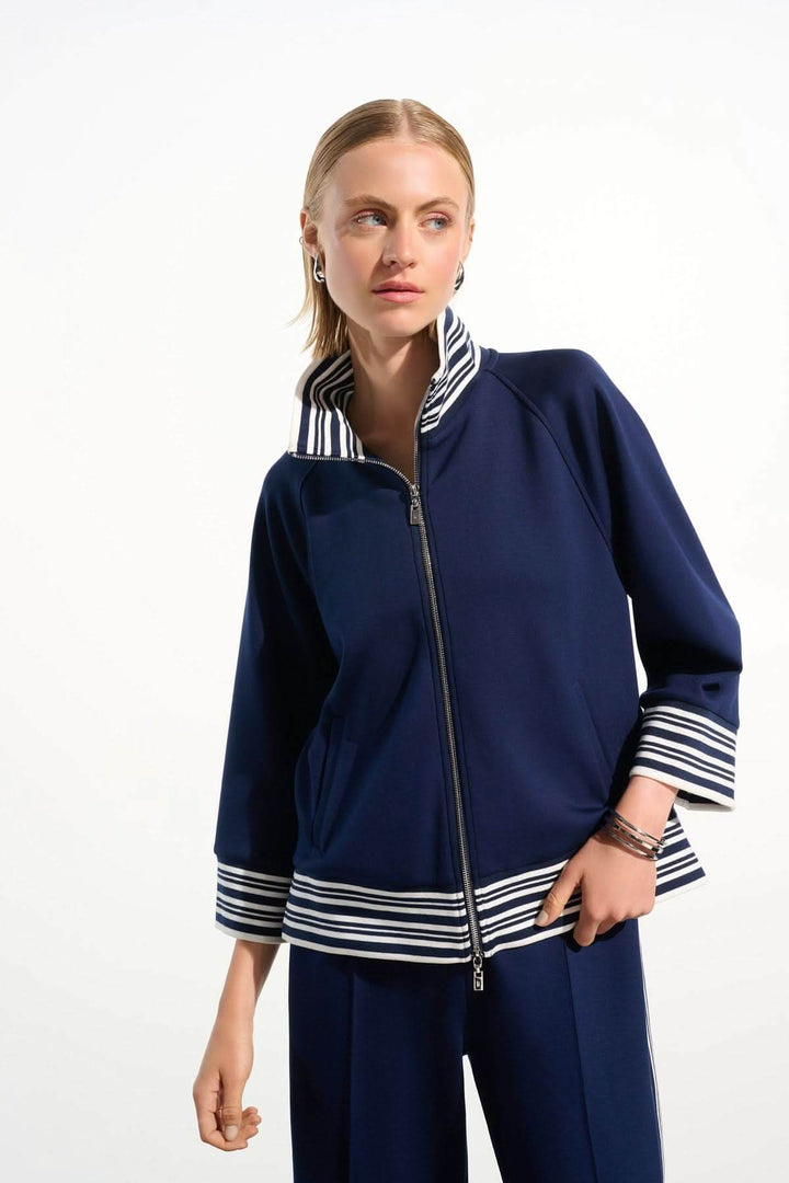 Femme portant une veste zippée à rayures contrastantes, manches trois-quarts, idéale pour un style chic et décontracté.