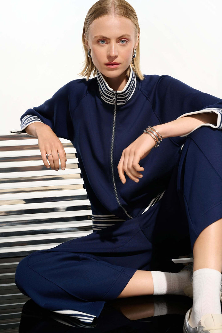 Femme portant une veste zippée à rayures contrastantes avec col chemisier, idéale pour un look décontracté et chic.