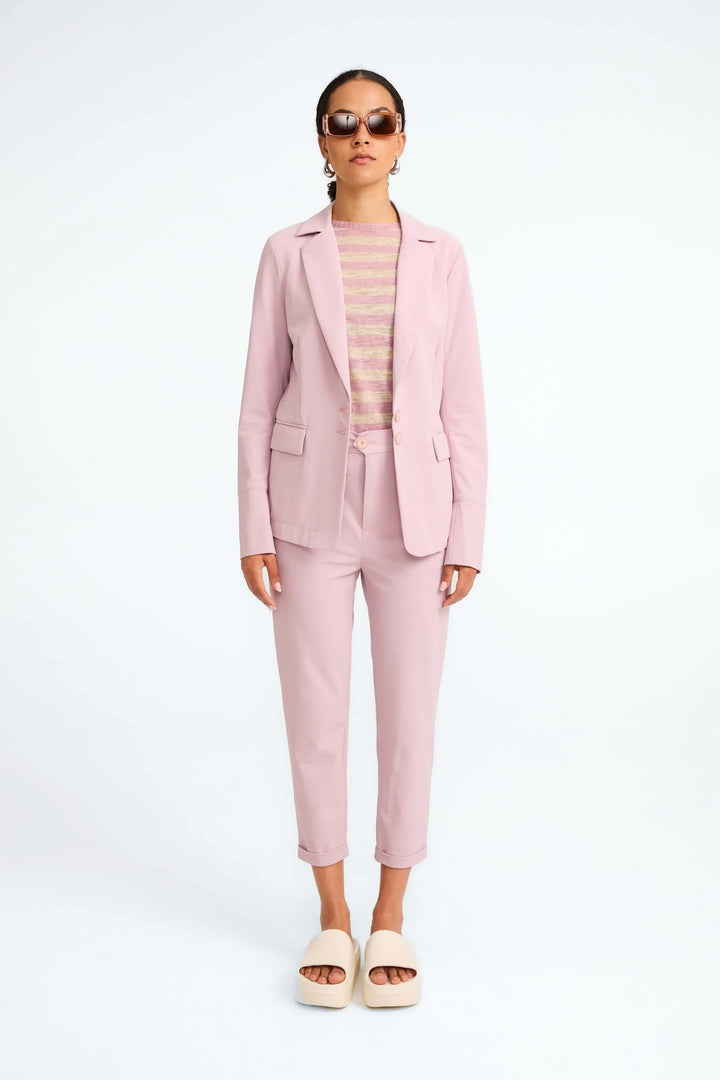 Veston Amsterdam structuré en rose, porté avec un haut rayé et un pantalon coordonné pour un look moderne et élégant.