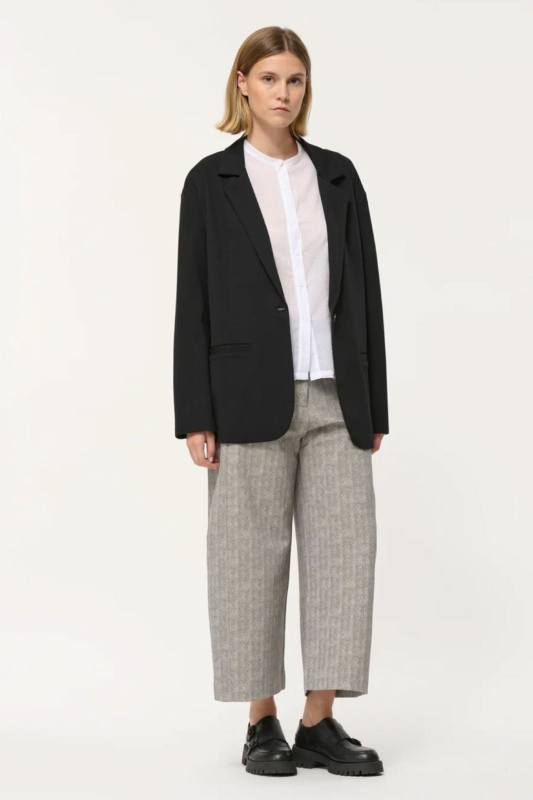 Veston Cayden noir à coupe droite, manches longues, porté avec chemise blanche et pantalon ample.