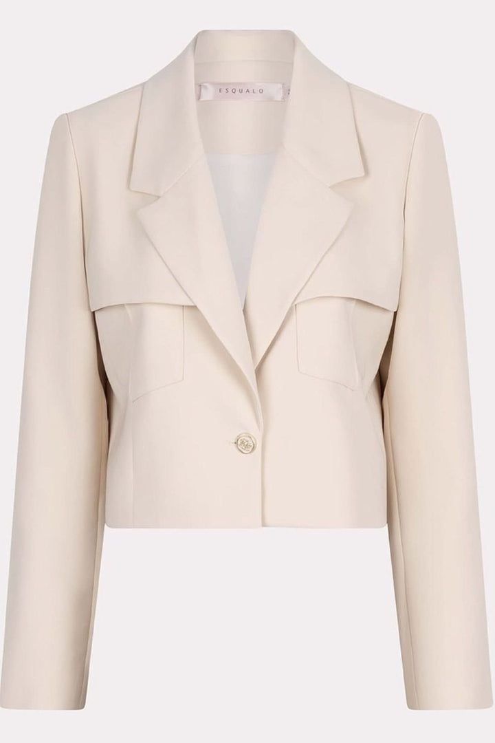 Veston court structuré beige avec poches surdimensionnées et bouton doré, style moderne et féminin.