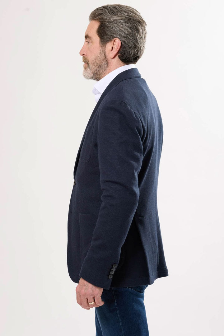 Homme portant un veston décontracté bleu marine, vue de profil, avec une coupe souple pour un style élégant.
