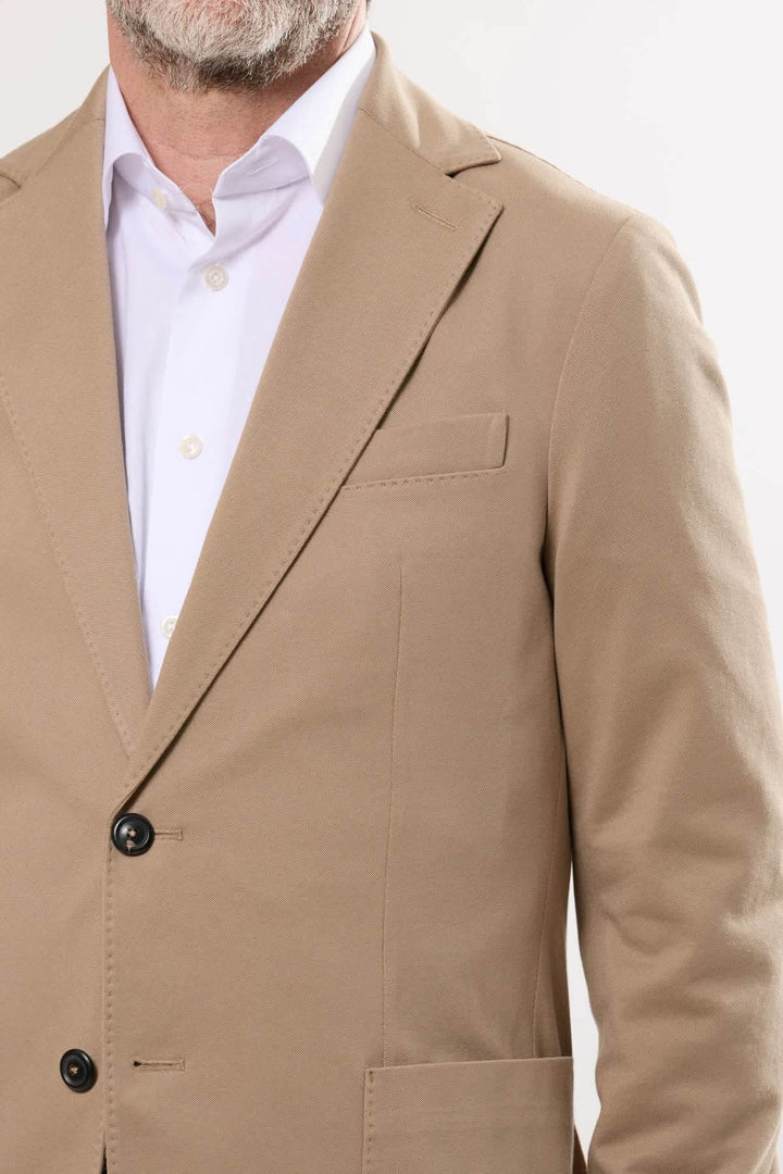 Veston en coton extensible beige avec fermeture à deux boutons et poche plaquée, idéal pour tenues habillées ou décontractées.