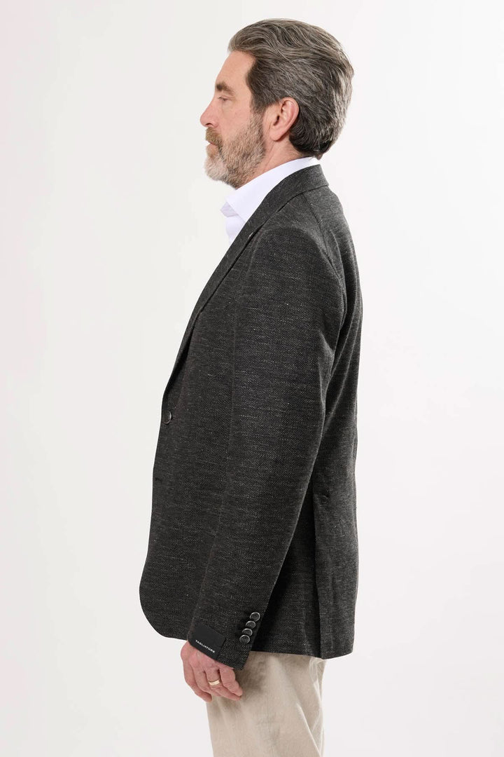 Veston noir texturé en matière chinée, vu de profil, alliant élégance classique et modernité.