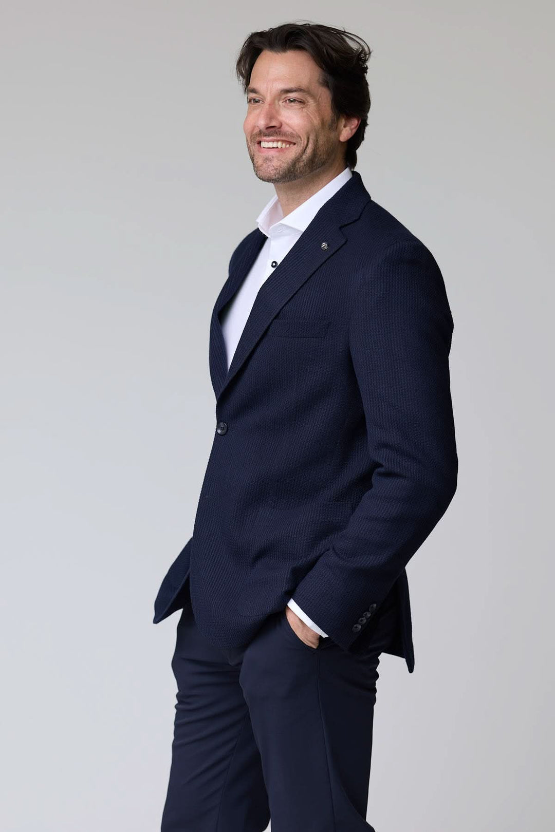 Homme portant un veston en tricot structuré avec une chemise blanche, décontractée élégance, mode moderne, coupe semi-ajustée.