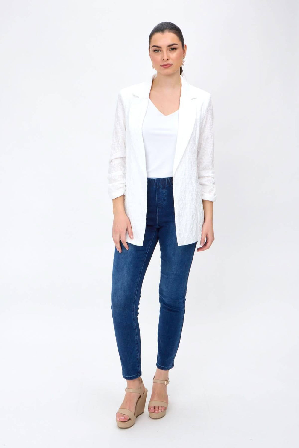 Veston léger ouvert, élégant avec manches froncées, porté par mannequin en jeans et talons, style décontracté.