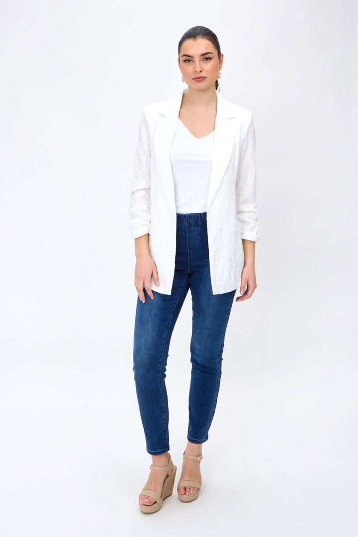 Veston léger ouvert, élégant avec manches froncées, porté par mannequin en jeans et talons, style décontracté.