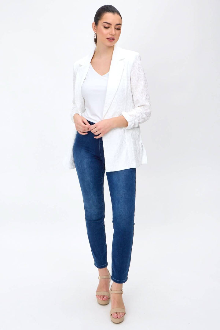 Veston léger blanc avec manches longues, porté par mannequin en jeans, élégant et décontracté.