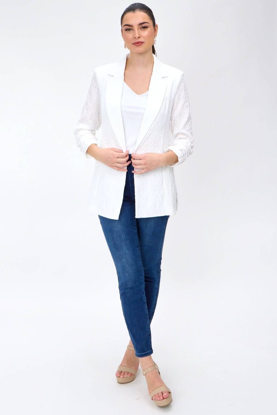 Veston léger blanc avec col à revers et manches froncées, porté par un mannequin avec un jean.
