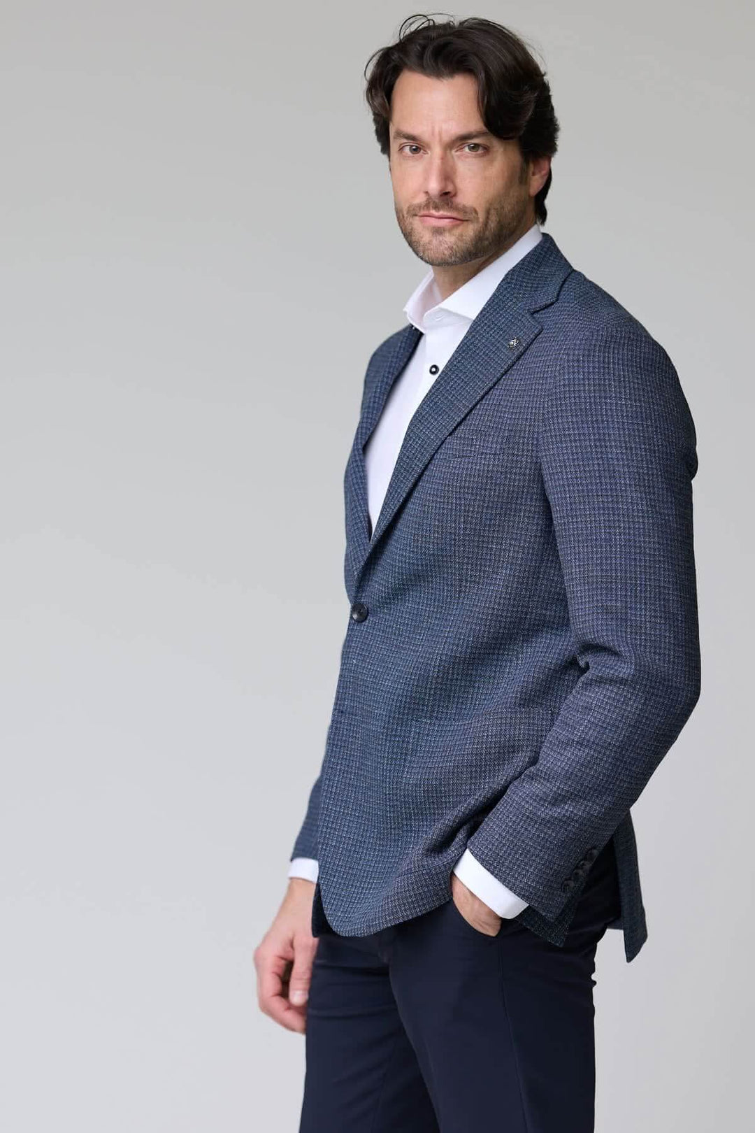 Homme portant un veston à motif texturé, bleu, avec col à revers. Parfait pour l'élégance moderne au bureau ou en événement formel.