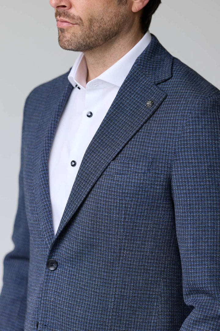 Homme portant un veston à motif texturé avec col à revers et fermeture à deux boutons, idéal pour les occasions formelles.