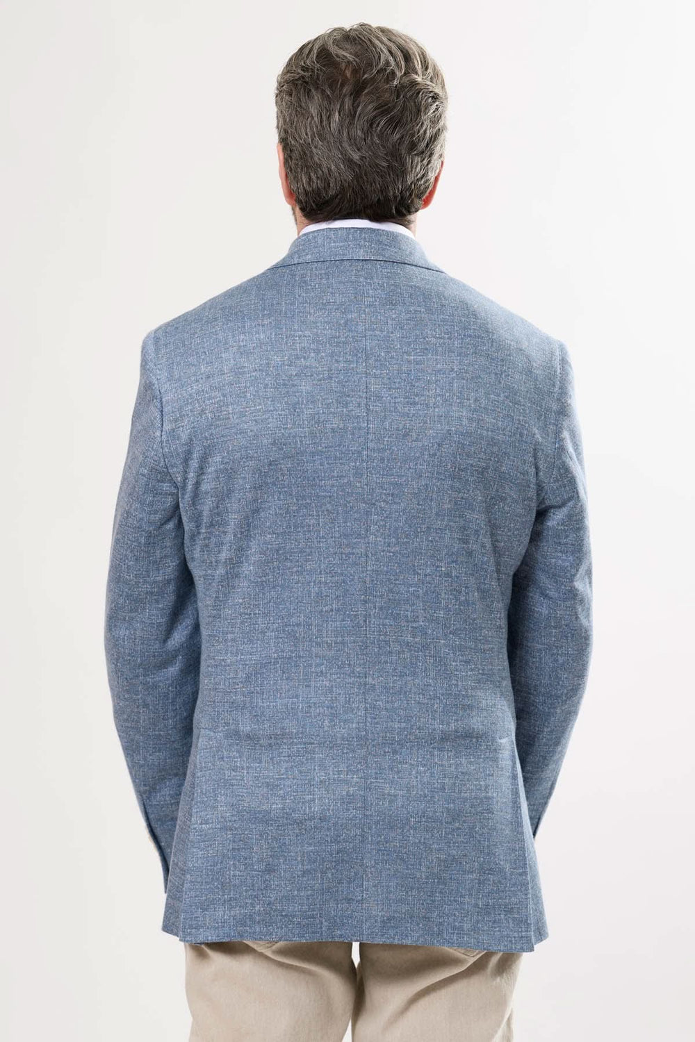 Homme portant un veston texturé bleu, vue de dos, élégant et moderne pour l'été.