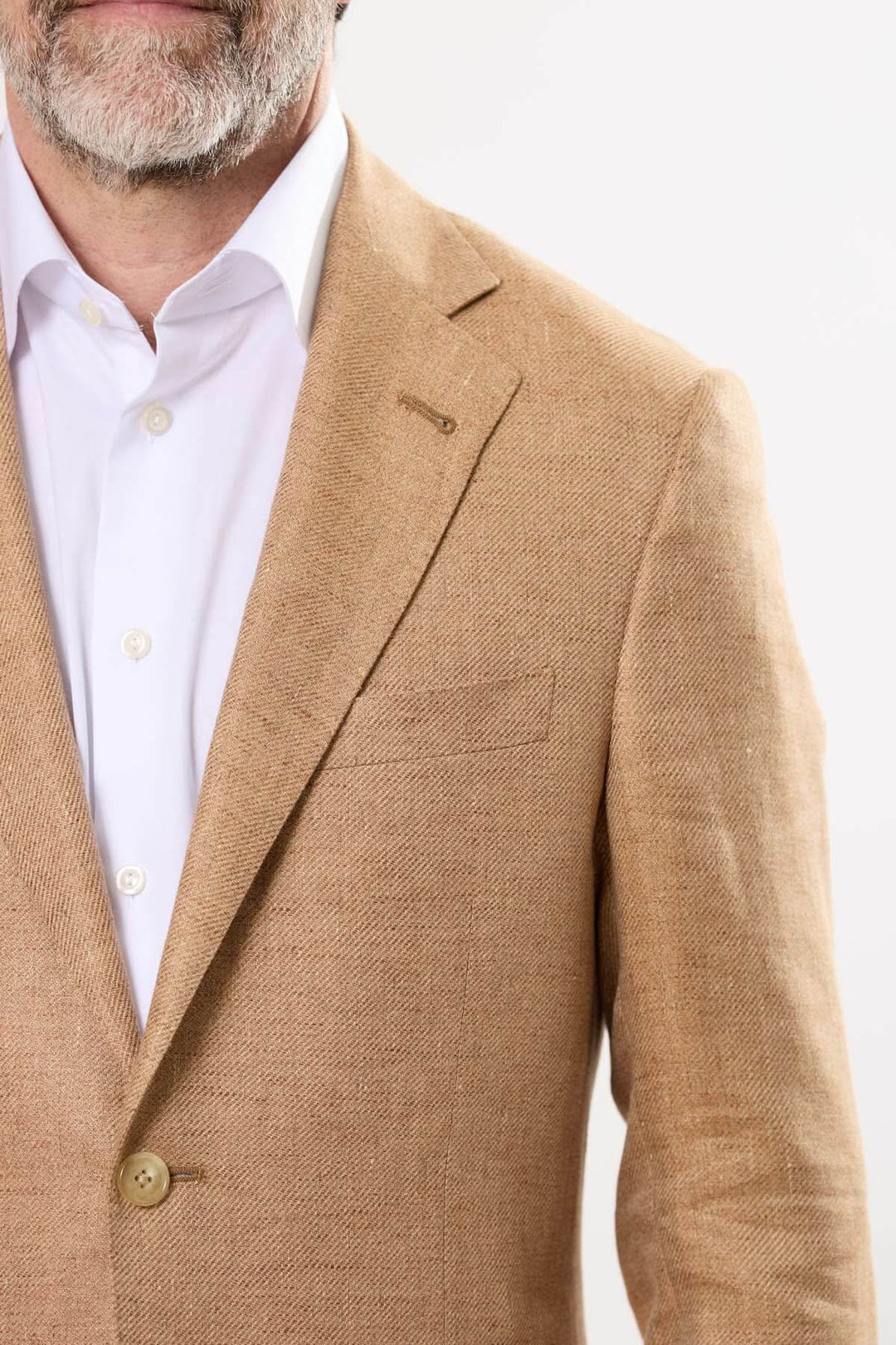 Homme portant un veston texturé beige avec une chemise blanche, affichant une élégance décontractée.