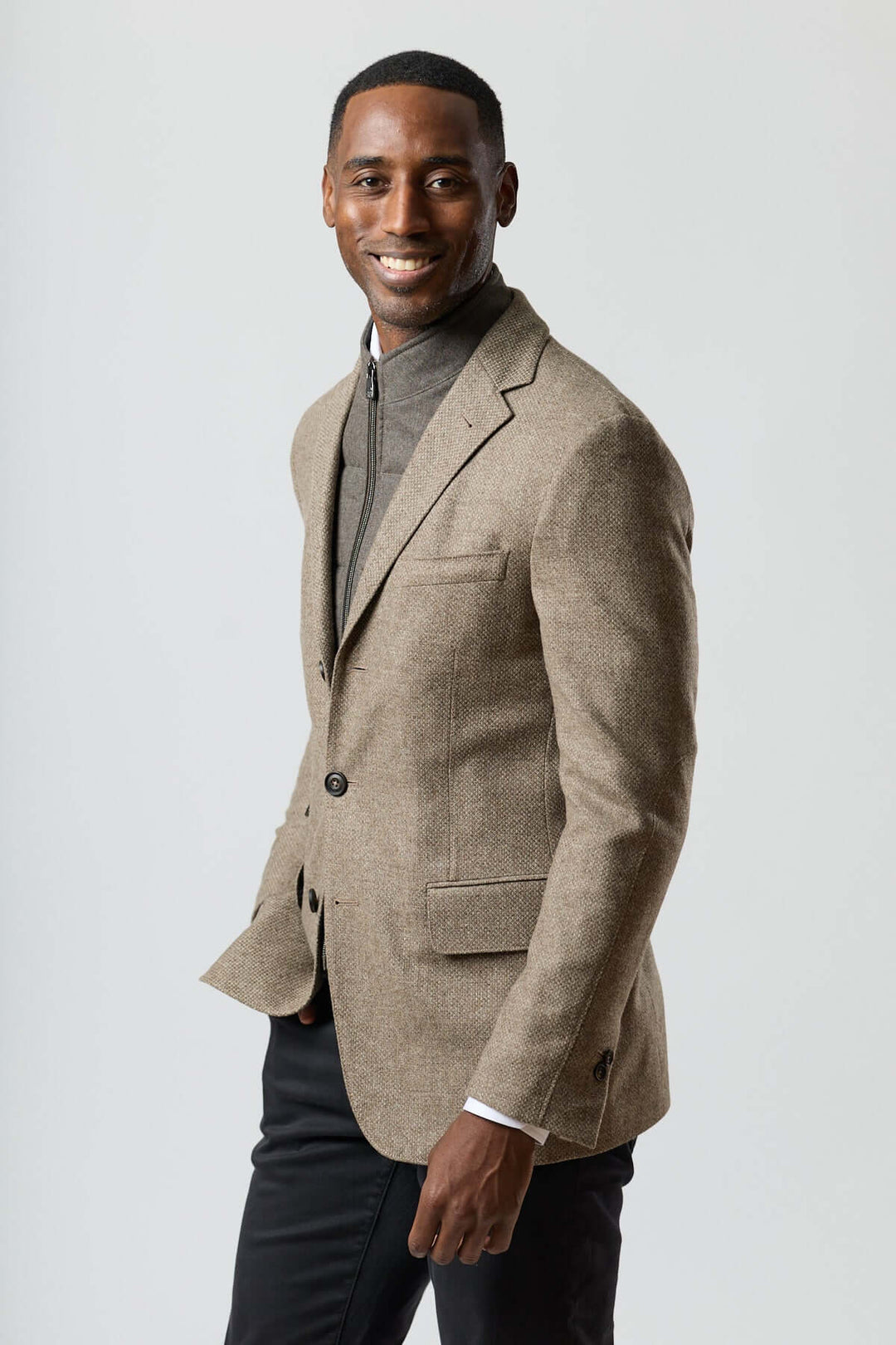 Homme portant un veston texturé en laine avec col amovible intégré, couleur beige doré, avec insert zippé pour une allure contemporaine.