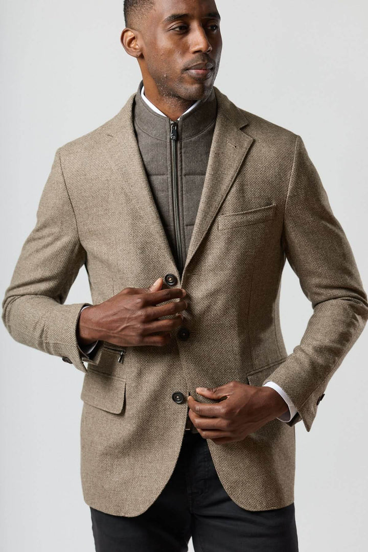 Veston texturé en laine avec col amovible intégré en tons beige doré et insert zippé, porté par un homme.