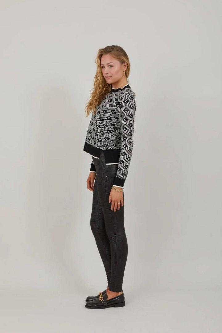 Femme portant un legging scuba noir et un pull graphique, montrant un look décontracté et chic.