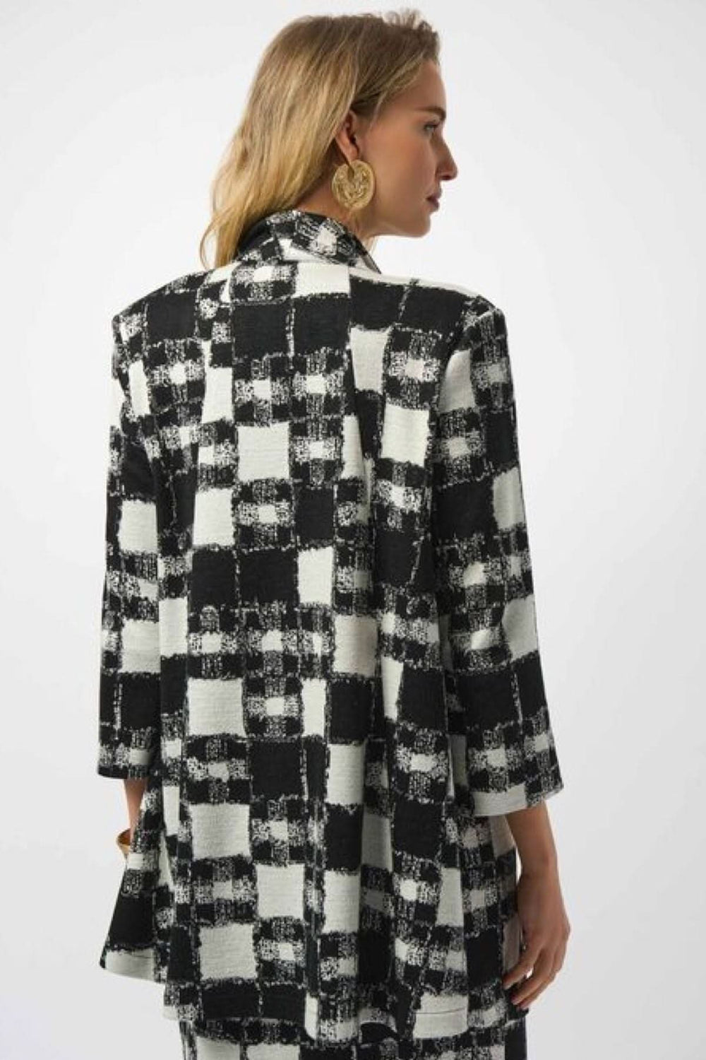 Vue arrière d'une veste longue à carreaux noirs et blancs avec col à revers et manches 3/4, style contemporain.