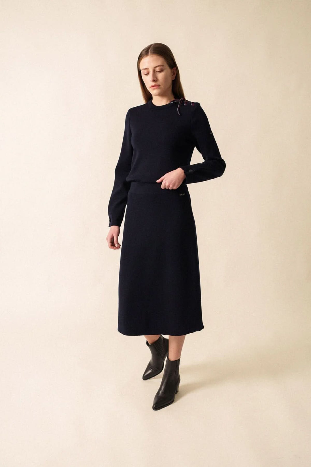 Chandail en maille à détail nœud sur l’épaule, femme portant une tenue élégante et féminine, parfait pour des journées fraîches.