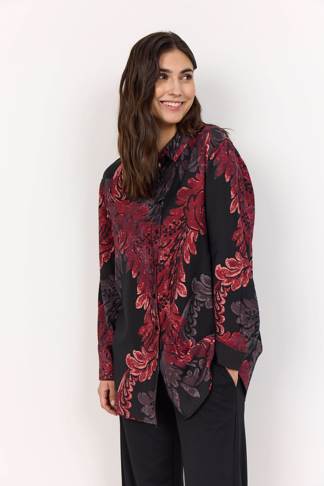 Chemise fluide au motif baroque avec imprimé feuillage, portée par une femme souriante.