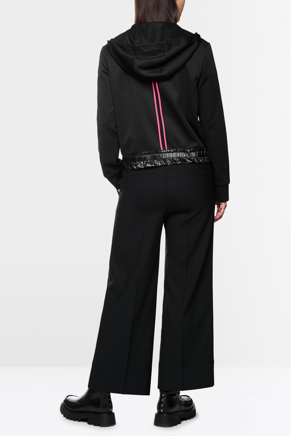 Veste à rayures contrastées, capuchon avec cordons, portée avec pantalon large et chaussures noires.