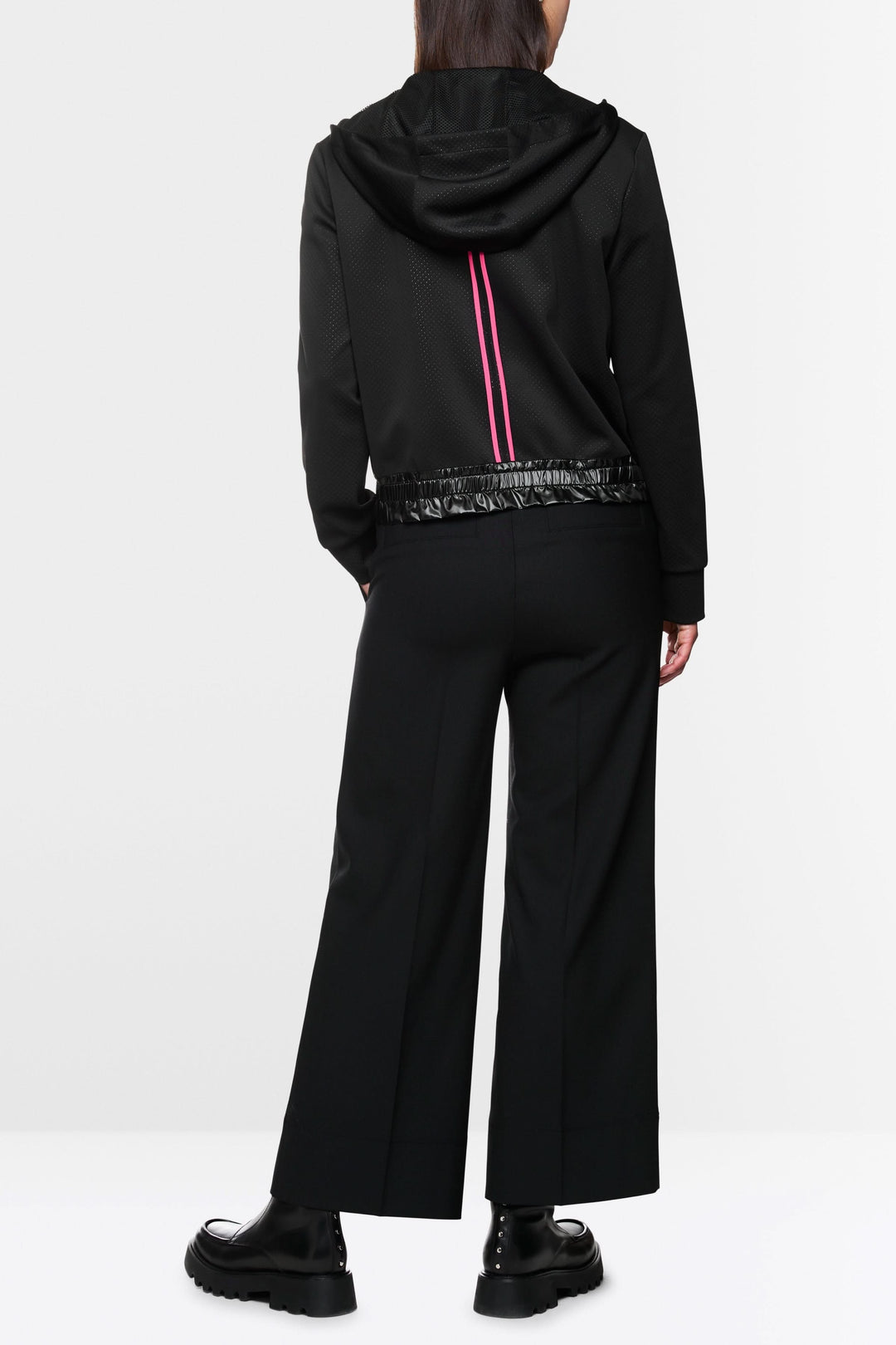 Veste à rayures contrastées, capuchon avec cordons, portée avec pantalon large et chaussures noires.