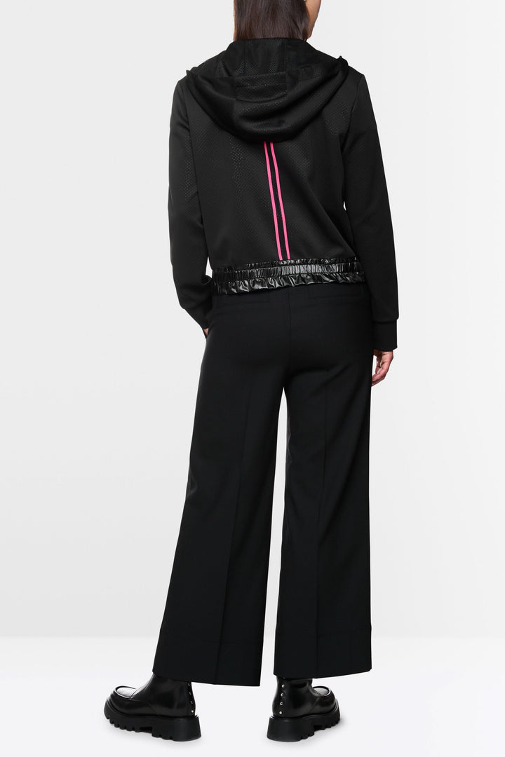 Veste à rayures contrastées, capuchon avec cordons, portée avec pantalon large et chaussures noires.