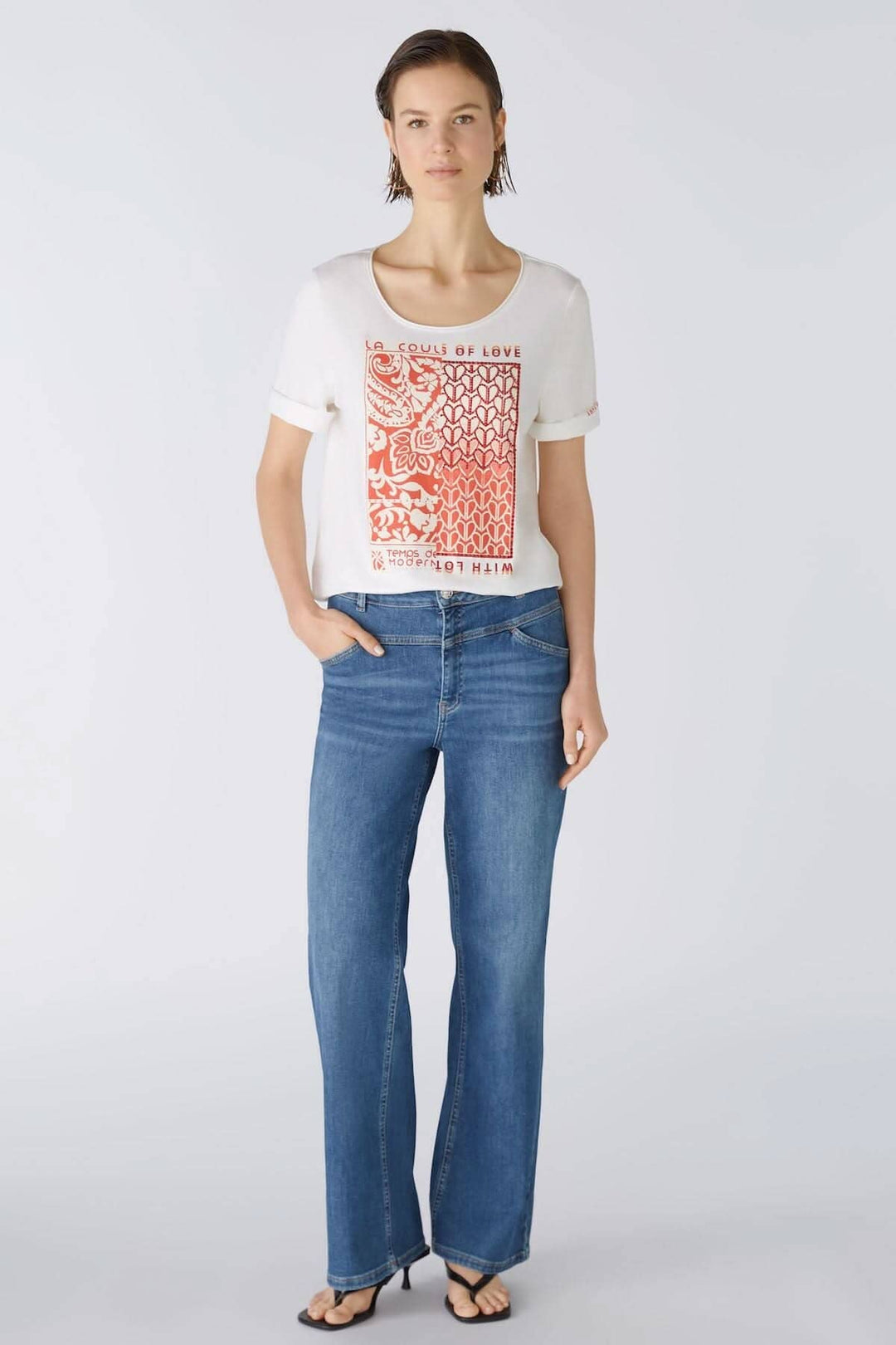 T-shirt avec imprimé graphique rouge, manches courtes, porté avec un jean bleu, style décontracté.