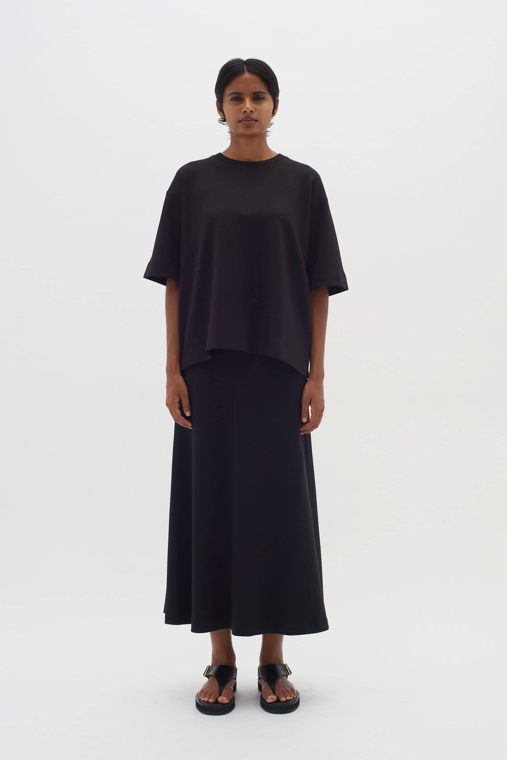 T-shirt ample et jupe longue noires, modèle féminin avec manches 1/2 et encolure ronde, look moderne et confortable.